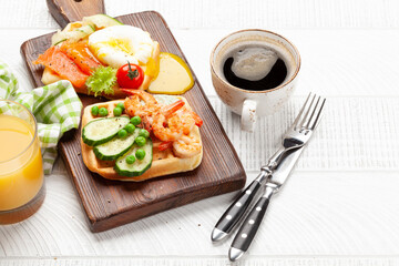 Breakfast waffles with fried eggs, salmon, cucumber and prawns