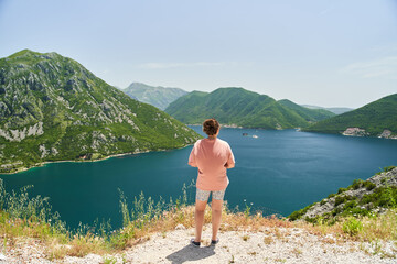 Fototapeta na wymiar a young girl admires the Bay of Kotor. Photo from the back