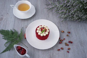 Red Velvet cake, classic cake on white plate and a cup of tea on the table.