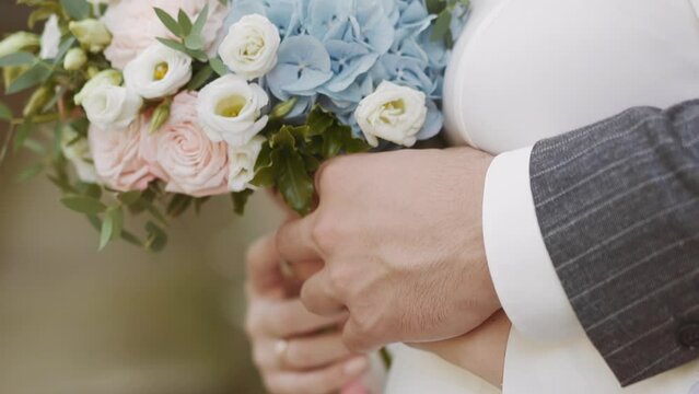 Careful man in jacket embraces wife holding gentle bouquet