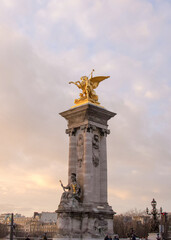 Fototapeta na wymiar Column with a gilded pheme sculpture of Pont Alexandre III at sunset in Paris, France