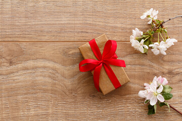 Obraz na płótnie Canvas Gift box with cherry flowers on the wooden background.