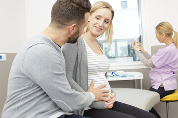 Fototapeta premium pregnant woman with her husband visiting the doctor in clinic
