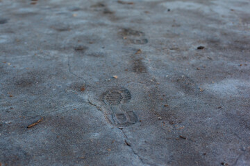 Texture of the dried earth with people traces. Gray background with cracks and hollows. Drought and lack of moisture in the soil. The consequences of abnormal heat. Environmental disaster. 