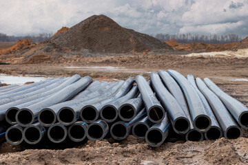 Water pipes for drinking water supply lie on the construction site. Preparation for earthworks for laying an underground pipeline. Modern water supply systems for a residential city.