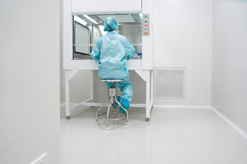 Unidentified microbiologist is testing the sample under the laminar air flow cabinet in the clean room of quality control laboratory in pharmaceutical industry.