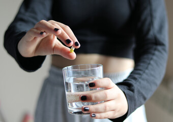 Young girl with a pill and a glass of water