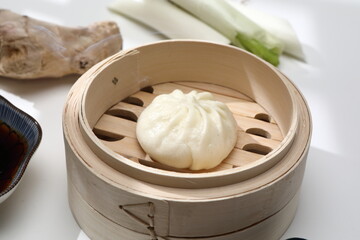 Delicious baozi, Chinese steamed meat bun is ready to eat on serving plate and steamer, close up, copy space product design concept.