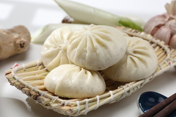 Delicious baozi, Chinese steamed meat bun is ready to eat on serving plate and steamer, close up, copy space product design concept.