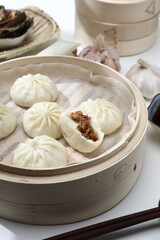 Delicious baozi, Chinese steamed meat bun is ready to eat on serving plate and steamer, close up, copy space product design concept.