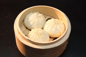 Delicious baozi, Chinese steamed meat bun is ready to eat on serving plate and steamer, close up, copy space product design concept.