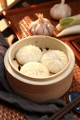 Delicious baozi, Chinese steamed meat bun is ready to eat on serving plate and steamer, close up, copy space product design concept.