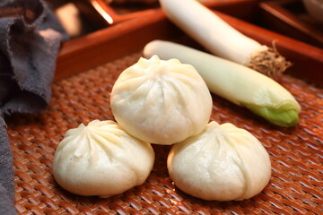 Delicious baozi, Chinese steamed meat bun is ready to eat on serving plate and steamer, close up, copy space product design concept.