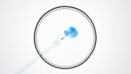 Top view macro shot of lab dropper injects blue liquid into transparent one with some bursting...