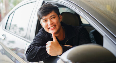 young asian man smile and show thumb up form car's window for good service and warranty concept