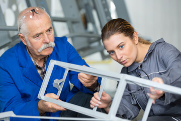 teacher watching student using soldering iron in vocational school