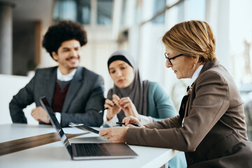 Mature insurance agent having consultations with Muslim couple in her office.