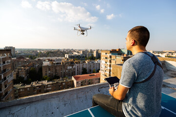 Young technician man flying UAV drone with remote control in city