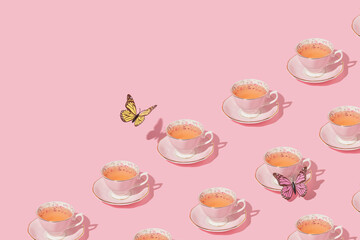 Butterflies flying above vintage cups of tea on pastel pink background. 80s, 90s retro aesthetic...