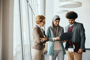 Multiracial group of business colleagues working on laptop at corporate office.