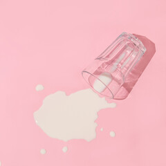 Creative layout with  glass of spilled milk on pastel pink background. 80s, 90s retro aesthetic...