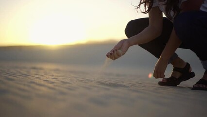 young female traveller gran handful of sand standing in sandal over dry desert during sunset, explore remote nature Mother Earth