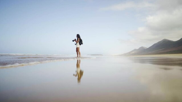 Young female freelance creative photographer walking on ocean tropical woman capturing beauty of Mother Earth in Fuerteventura island Spain travel tourism destination