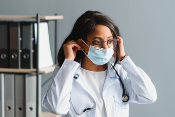 medicine, profession and healthcare concept - close up of african female doctor or scientist in protective facial mask.