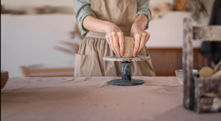female potter works with clay, close-up of female hands hold a piece of wet clay in her hands. The potter creates the product. the formation of handmade dishes. Art and small business concept.