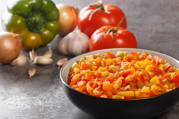 Delicious summer sofrito sauce from peppers, tomatoes, garlic and onions close-up in a plate on the table. horizontal