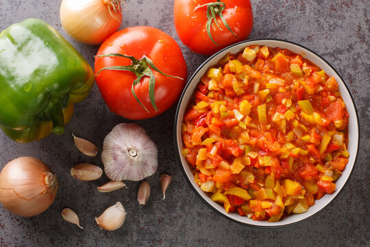 Delicious summer sofrito sauce from peppers, tomatoes, garlic and onions close-up in a plate on the table. horizontal top view from above
