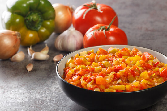 Delicious summer sofrito sauce from peppers, tomatoes, garlic and onions close-up in a plate on the table. horizontal