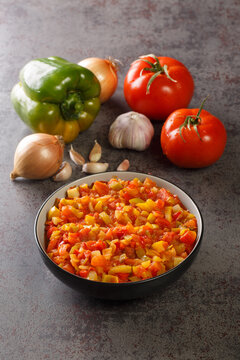 Mediterranean sofrito sauce from ripe peppers, tomatoes, garlic and onions close-up in a plate on the table. Vertical
