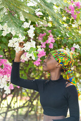 Gorgeous African girl standing under a magnificent bougainvillea tree admiring the pink and white...