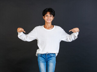 Studio closeup shot of Asian young LGBTQ gay glamour bisexual homosexual male model in casual outfit standing smiling holding two hands and fingers pointing blank copy space on black background