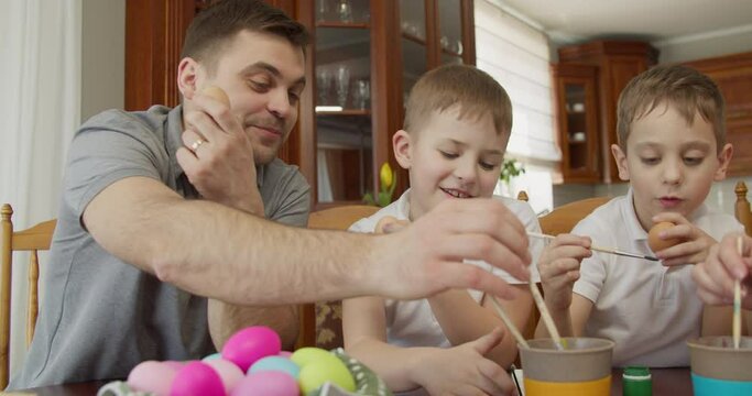the father with two sons paints Easter eggs. preparations for the Easter holiday