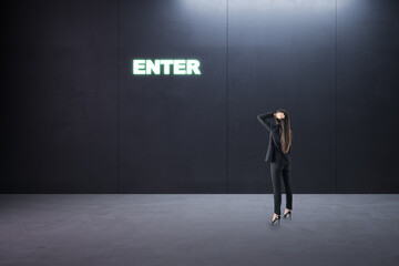 Thoughtful young businesswoman standing in concrete interior with entrance to success. Way and opportunity concept.