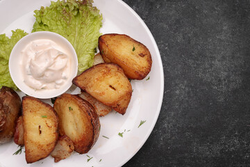 Homemade fried potatoes with sauce, on a dark background
