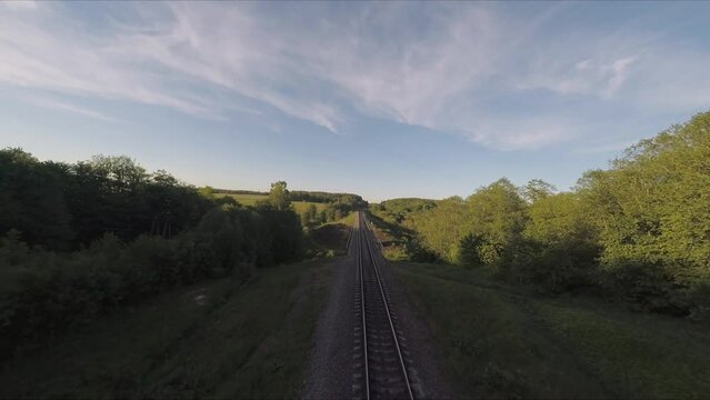 Flying over the bridge and the river on a drone. Flying along the railway rails. Flight at sunset. A sunny summer day. Aerial photography . FPV flights. High-speed flights on a drone.
