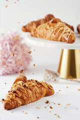 Croissant on a white background in the composition. Selective focus. Close-up. Nuts fall on the croissant