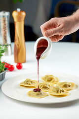 Ravioli in a white plate pour the sauce in the composition of the ingredients. Decorating the dish by the chef