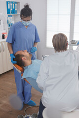 Obraz premium Dentist assistant checking patient mouth analyzing caries infection using stomatological instrument during orthodontic examination in dental office room. Concept of dentistry procedure