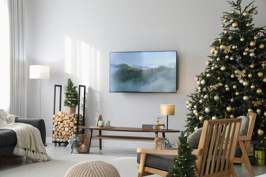 Modern TV Set On Light Wall In Room Decorated For Christmas