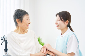 Obraz premium 介護士と車椅子に乗る高齢者 室内