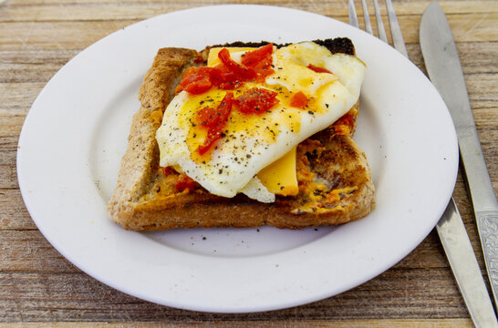 A fried egg on toast isolated on a small white side plate