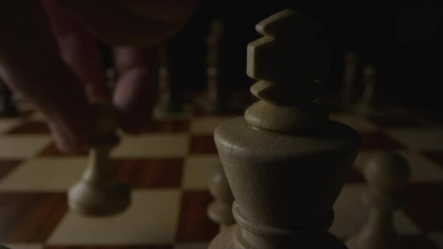 Chess player&rsquo;s fingertips move Queen&rsquo;s pawn forward two spaces on board to D4. Low angle static shot.