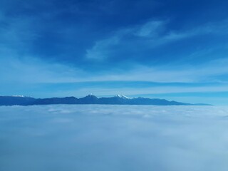 View of Gorenjska region of Slovenia covered in low level stratus clouds with snow covered peaks of Kamnik-Savinja alps in the background