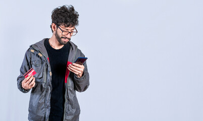 Man holding credit card and cell phone, guy paying from his phone with credit card, electronic...