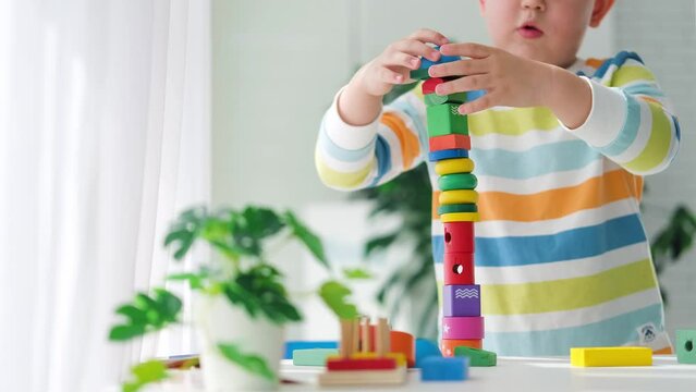 A little boy plays with wooden toys and builds a tower. Educational logic toys for children. Montessori games for child development. Children's wooden toy.