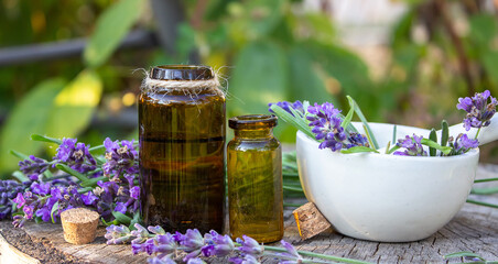 Herbal oil and lavender flowers on a wooden background. Nature.